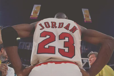 Michael Jordan celebrating with arms in power pose, wearing his iconic white Bulls #23 jersey